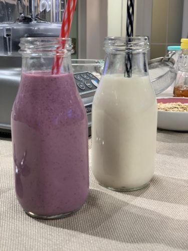 wild blueberry oat milk next to regular oat milk in jars