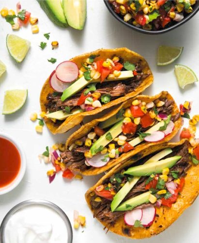 three flank steak tacos with charred corn salsa and avocado