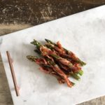 prosciutto wrapped asparagus on marble tray