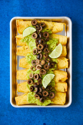 Olive and Refried Bean Taquitos on a pan with blue background